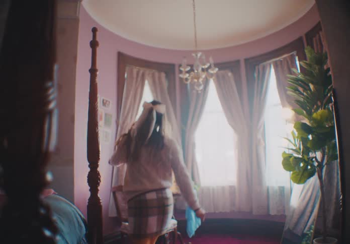 Woman wearing a skirt with tights dances in her bedroom near a round bay window