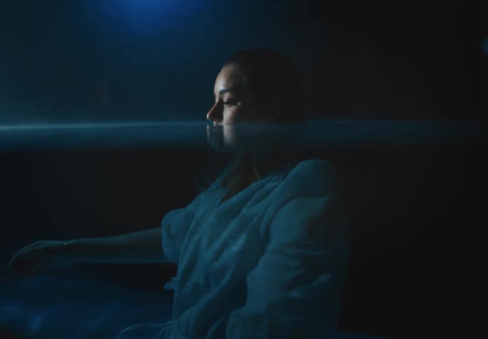 Woman nearly nosedeep in water lets her arms float up to the surface