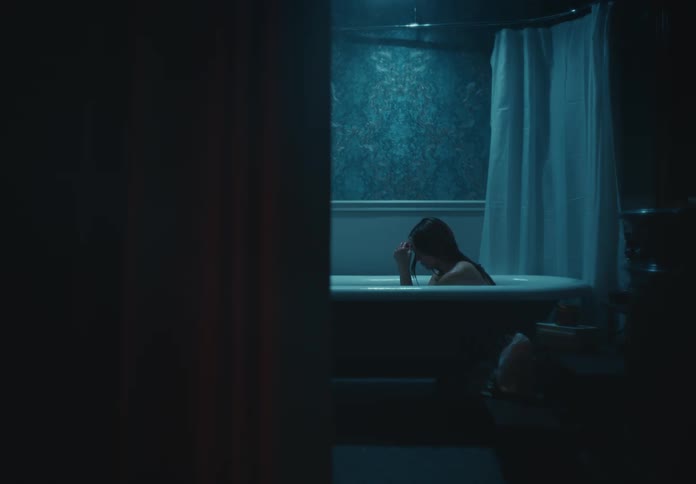 A woman looks really upset as she sits in a bathtub