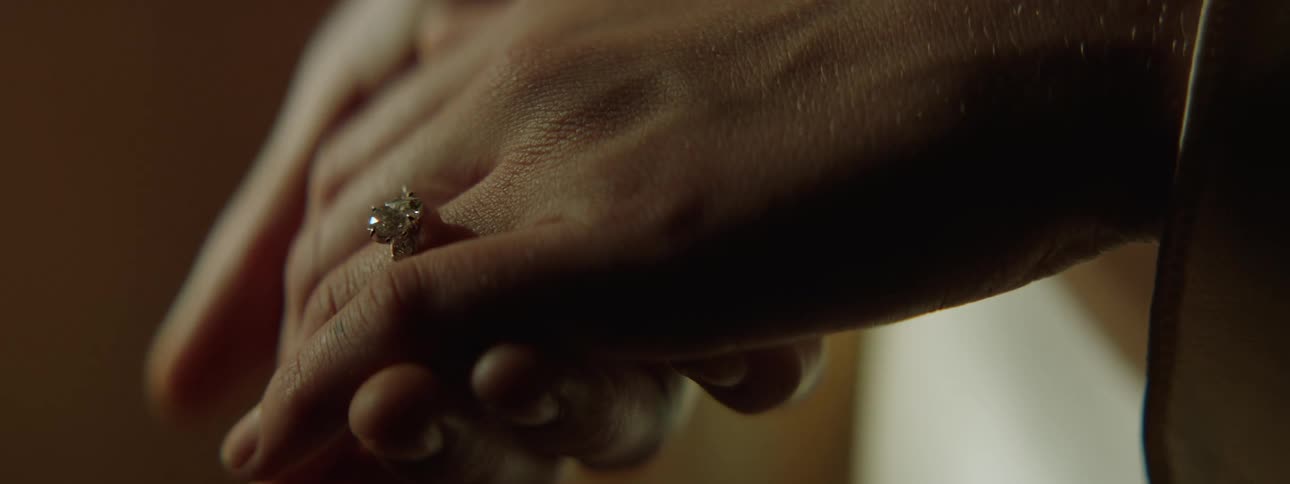 A closeup shot of two hands gently holding with one hand wearing a diamond engagement ring