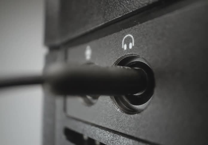 A person plugging an audio connector into a device with an audio input