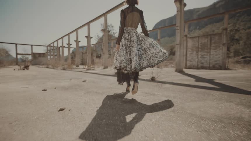 A woman is walking outside while wearing a long dress