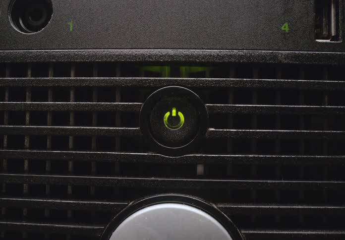 A person presses the power button on their computer