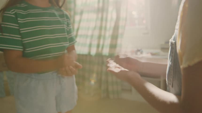 Two little girls playing with their hands in a room during the day