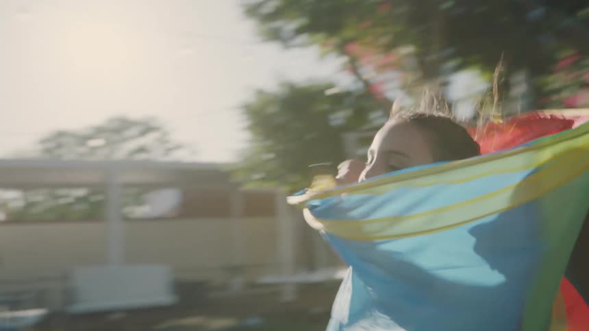 Girl in a plastic tube runs through the backyard of her home on a sunny summer day