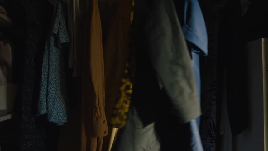 Little girl hiding among clothes