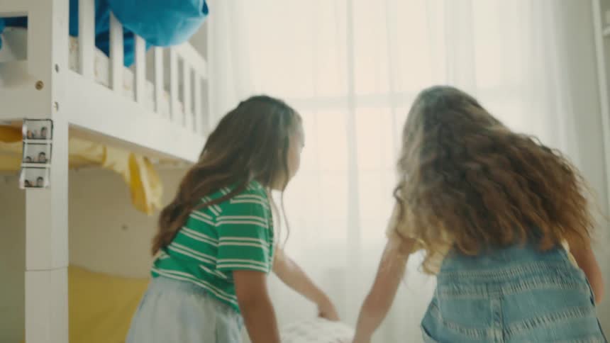 Two girls hide underneath a blanket in the corner
