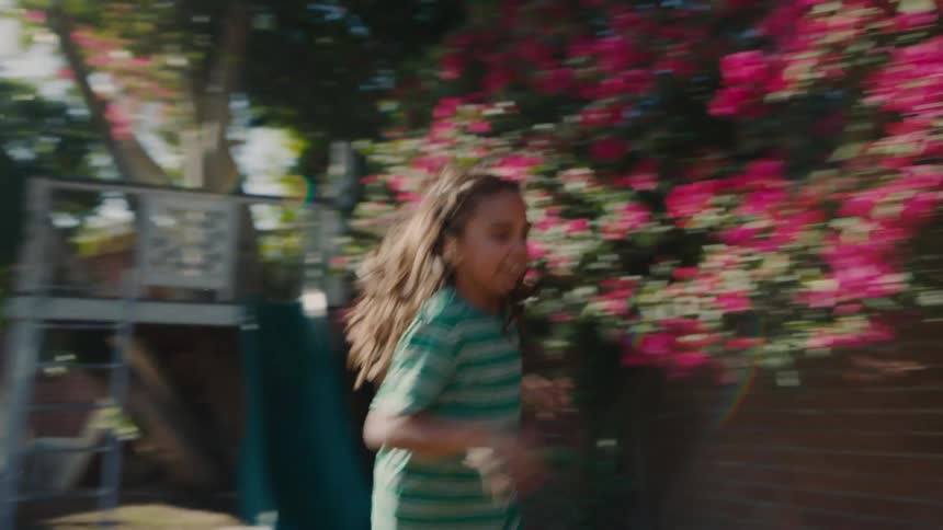 Two young girls running around a backyard playing on a sunny morning
