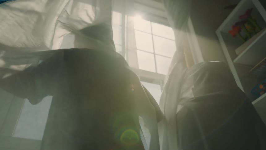 Two children play in the drapes of a window
