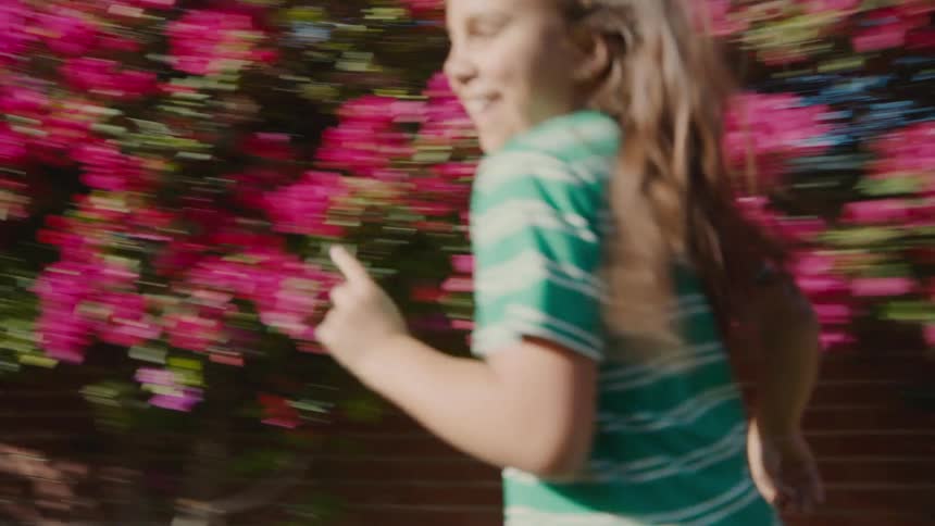 Two children are joyfully running and playing outside in a suburban backyard on a sunny day