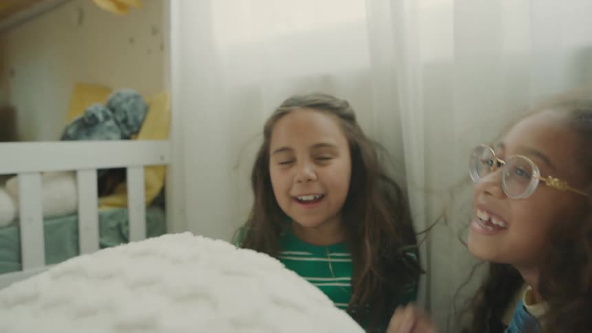 Person pulling a green sheet and finding two girls hiding