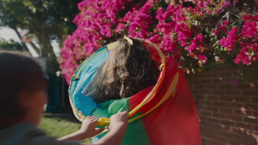Children playing running through the backyard of a house