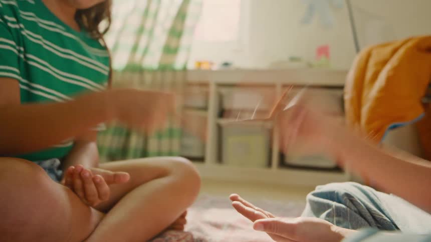 Two children sitting in a bedroom playing rockpaperscissors