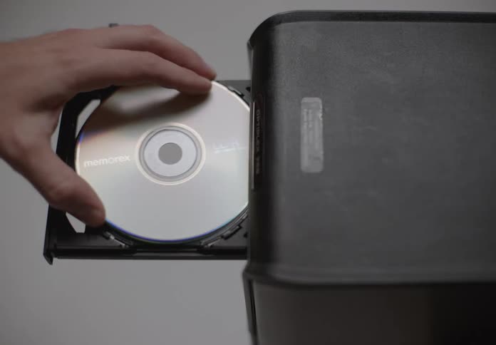 A person is inserting a memorex cd into a disc drive