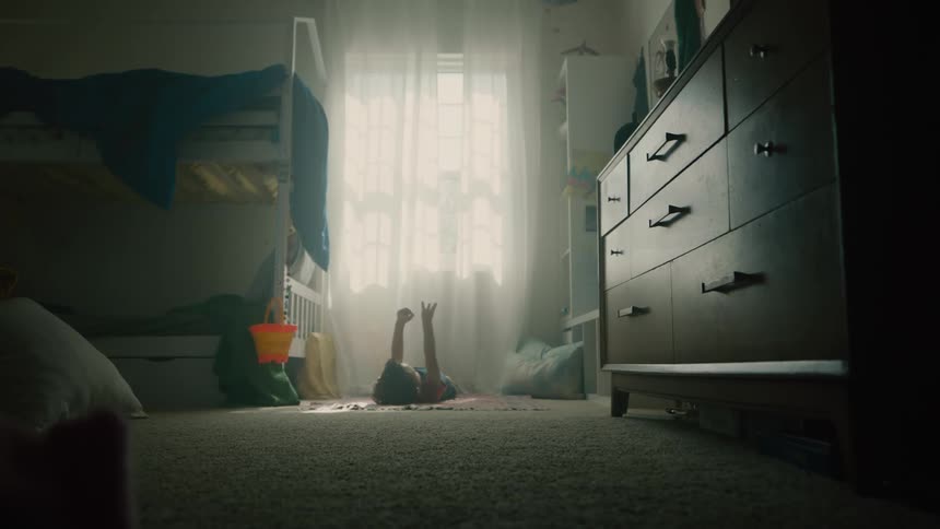 A child is laying down on the floor with their arms up