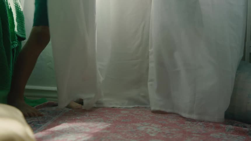 Two children hide behind the curtains