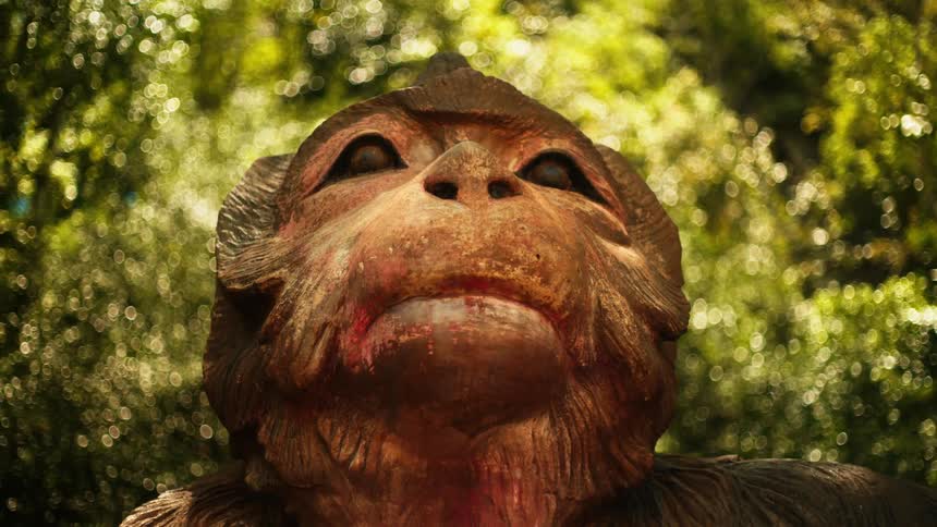 A wooden sculpture of an animal is in the forest