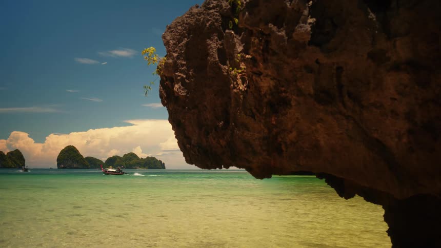 Landscape of a beach with crystal clear waters and a boat traveling in the background