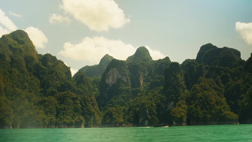 Greenish water on the edge of mountains covered in vegetation