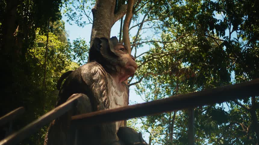 A large carving of a primate is at the top of a railing in the forest