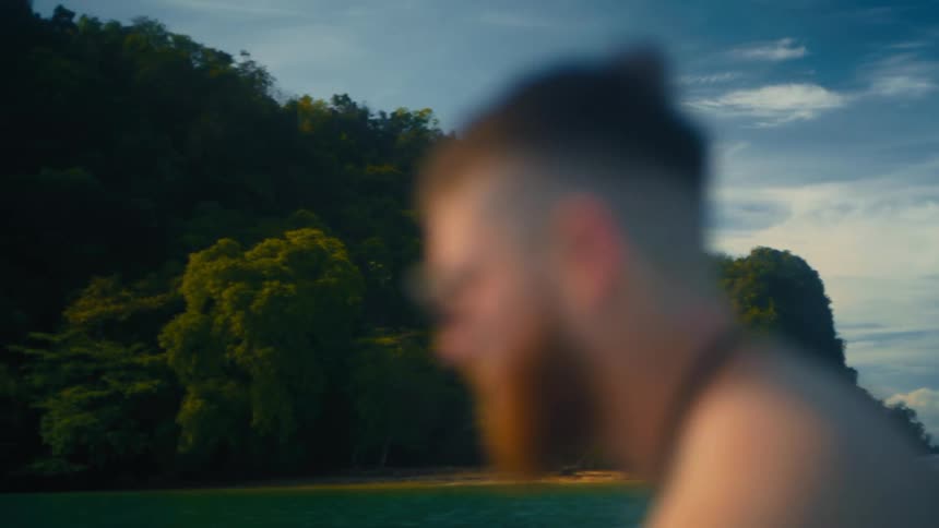 A man is passing by the small island covered in trees