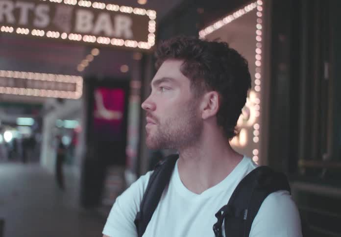 Man stands outside of a sports bar during the daytime