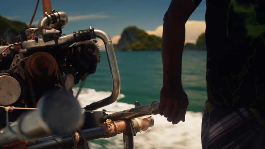 A man near a boat motor steering the boat on the sea
