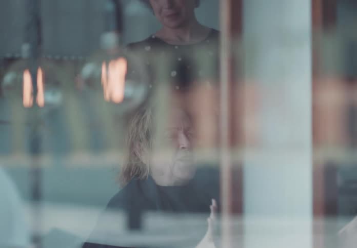 Beautician and her customer talk behind the reflective glass of the beauty shop during the day