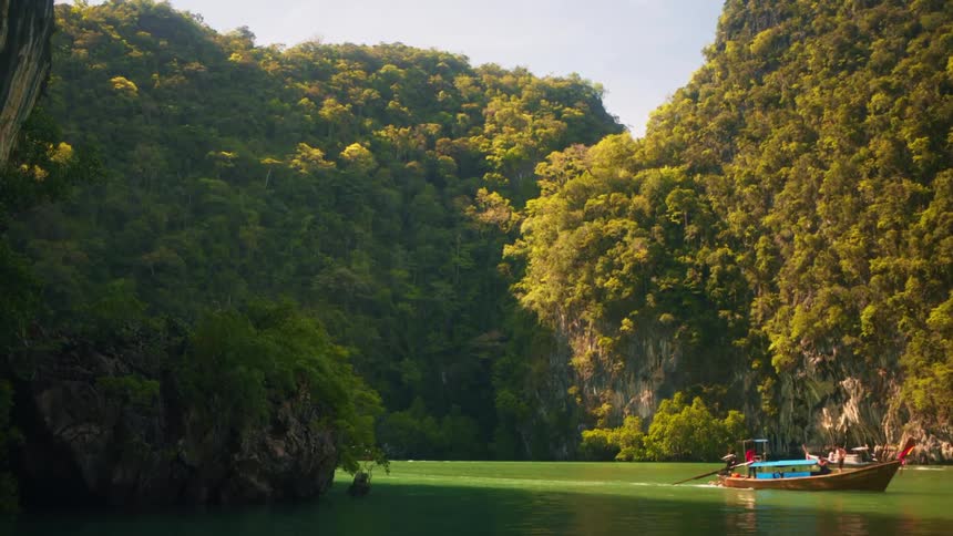Motorized canoes traveling through a sea of green water surrounded by forested mountains
