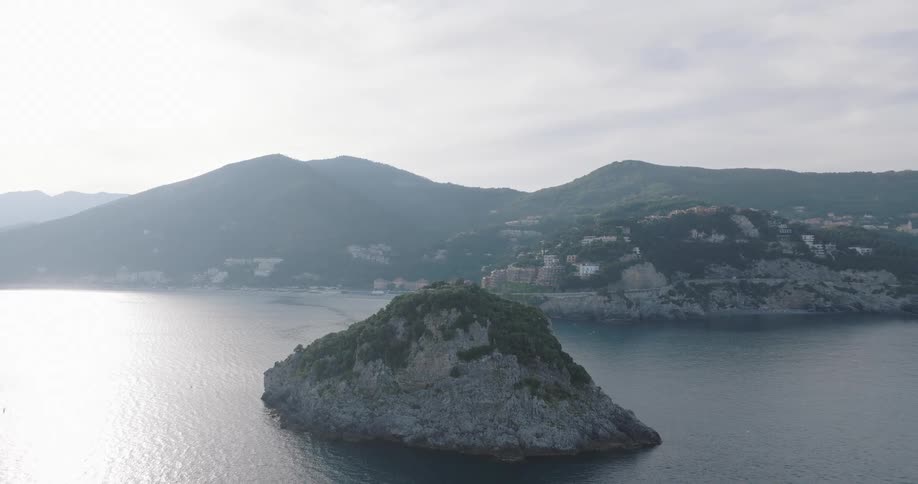 Aerial view of an island in the ocean with forested mountains in the background
