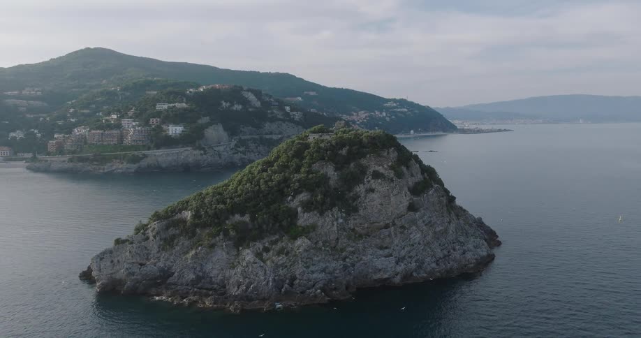The birds fly around the small mountain in the ocean