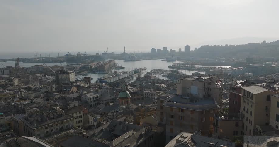Aerial view of a port city with historic architecture and a busy marina under cloudy skies and a slightly hazy atmosphere