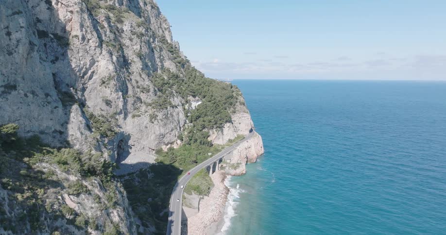 Cars driving on the long road on the side of the coastal mountain