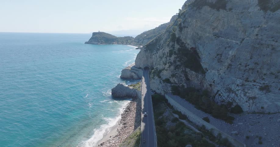 Aerial view of a highway along a beach and mountains