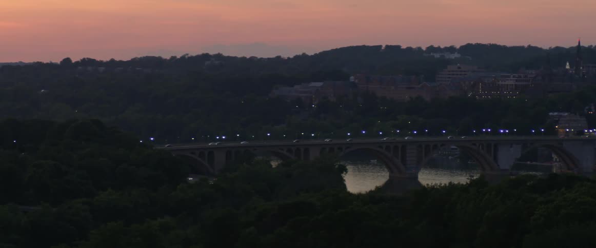 The cars ride over the bridge at dawn