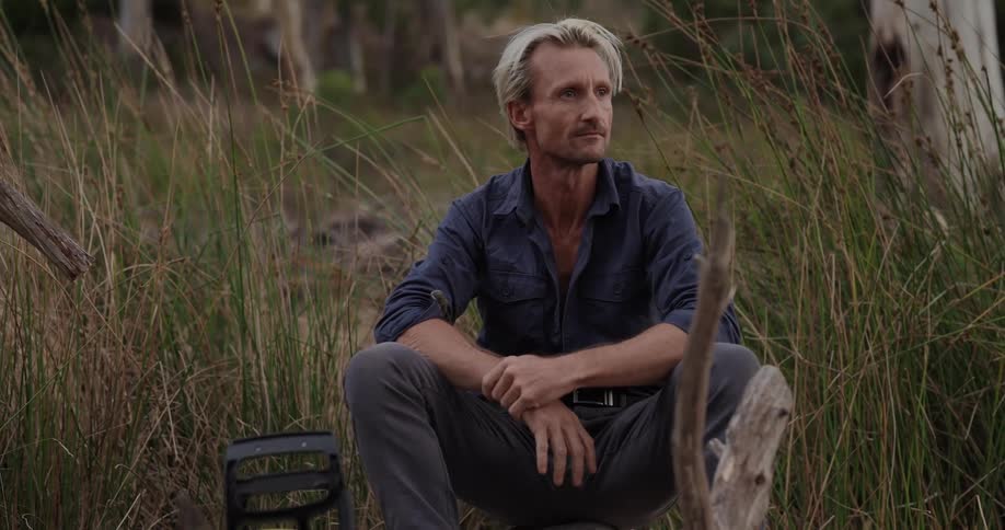 A footage of a man seating in the bush