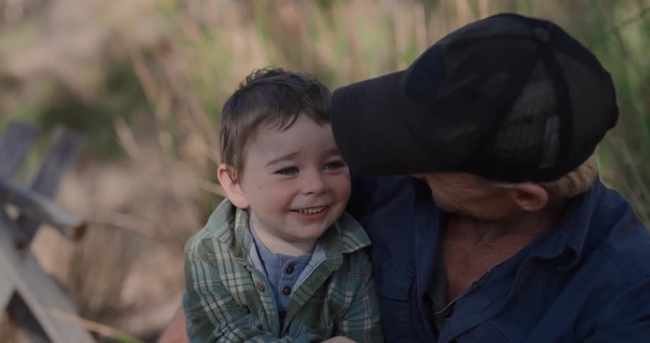 A father and son laugh together as they sit outside