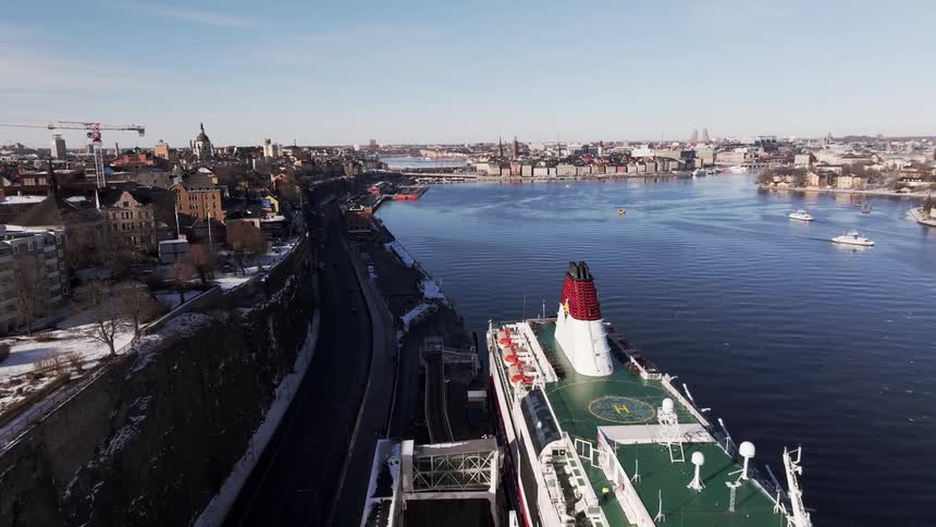 A large ship docked near a road in a big city