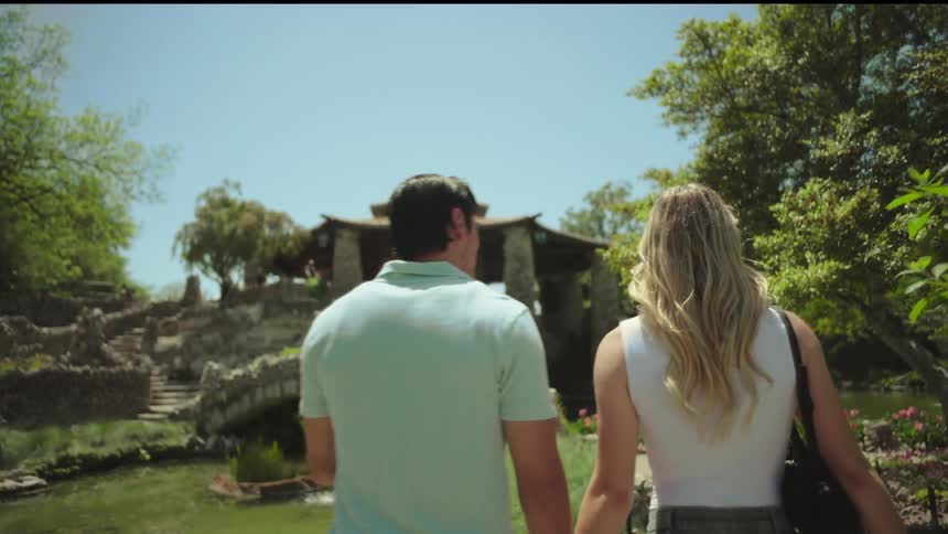 A couple walking hand in hand through a public park at midday