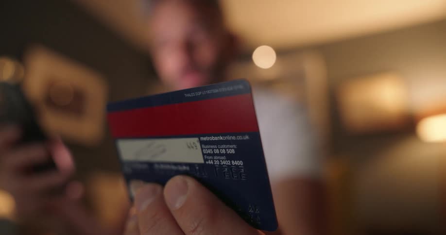 A man is typing in his credit card number to pay on the phone