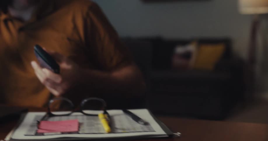 Man sitting talking on cell phone on a call and picking up a calculator