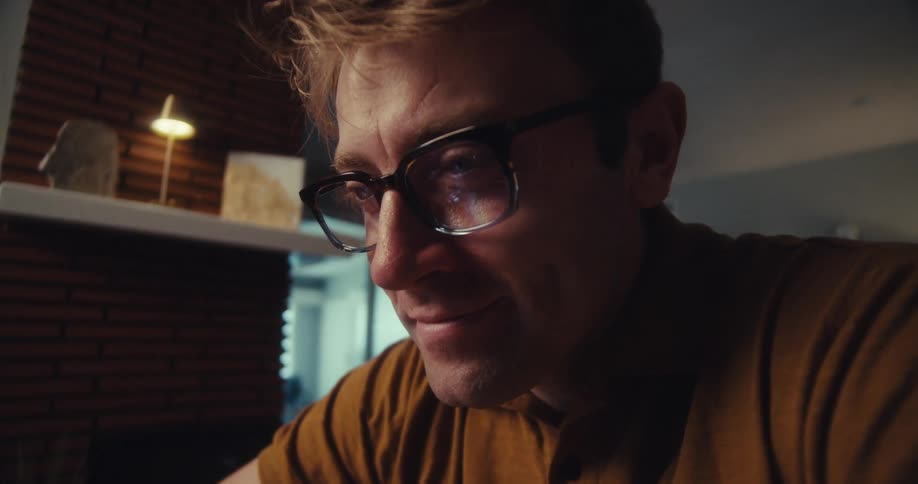 A man smiles while having a video call at home clearly enjoying the conversation
