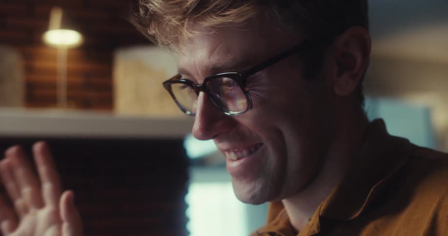 Smiling man with glasses making the hello sign with his hand