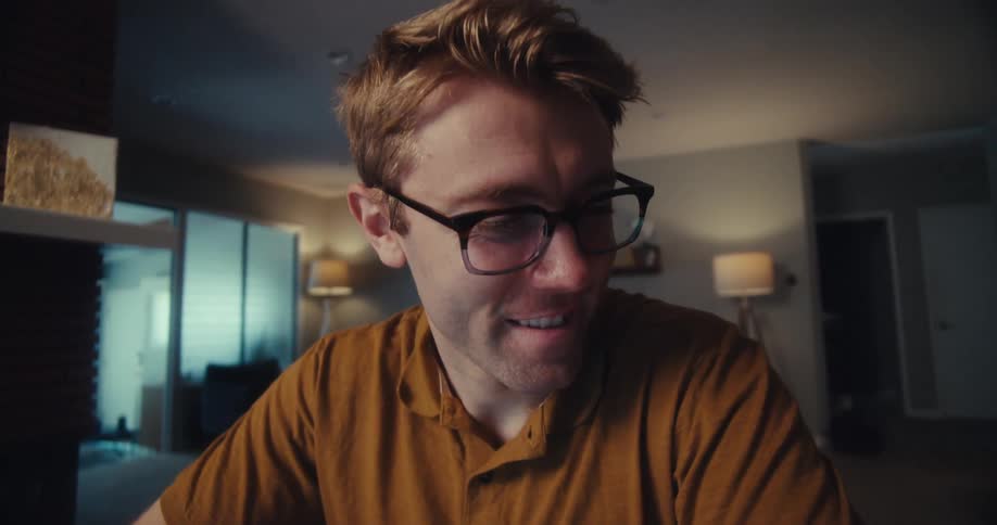 Thoughtful and cheerful man with glasses using a calculator