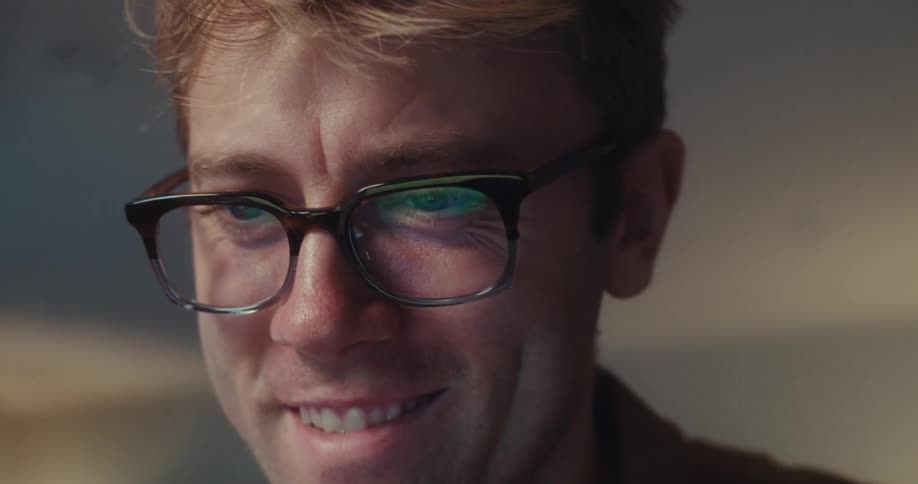 A man looks happy and excited while smiling at his laptop screen