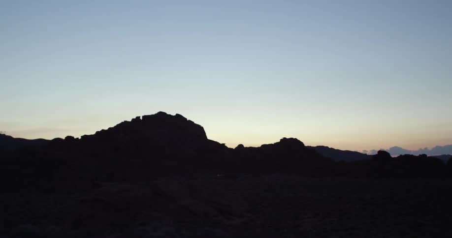 The sun peeks over a rocky formation