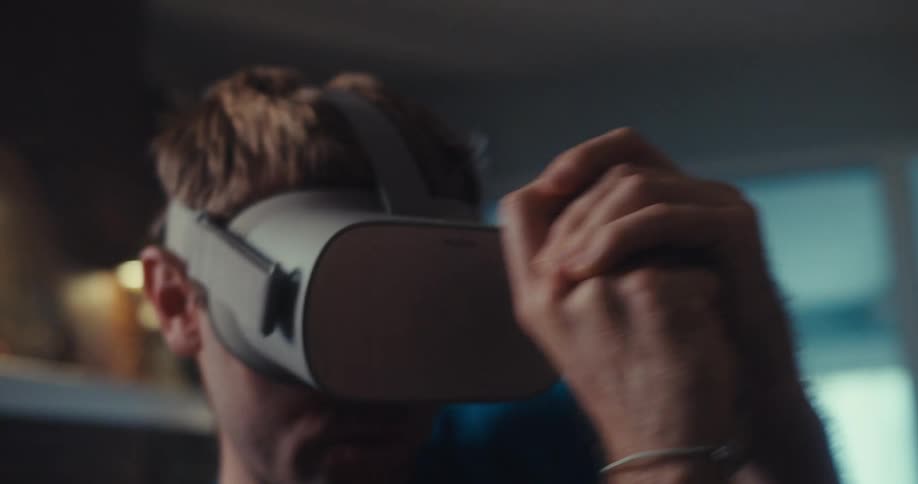 Man wearing a virtual headset aims while playing a game at home during the daytime