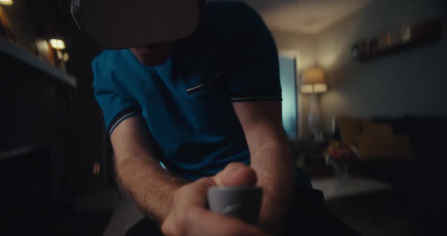 A man wearing a vr headset plays an immersive game in his living room using a motion controller