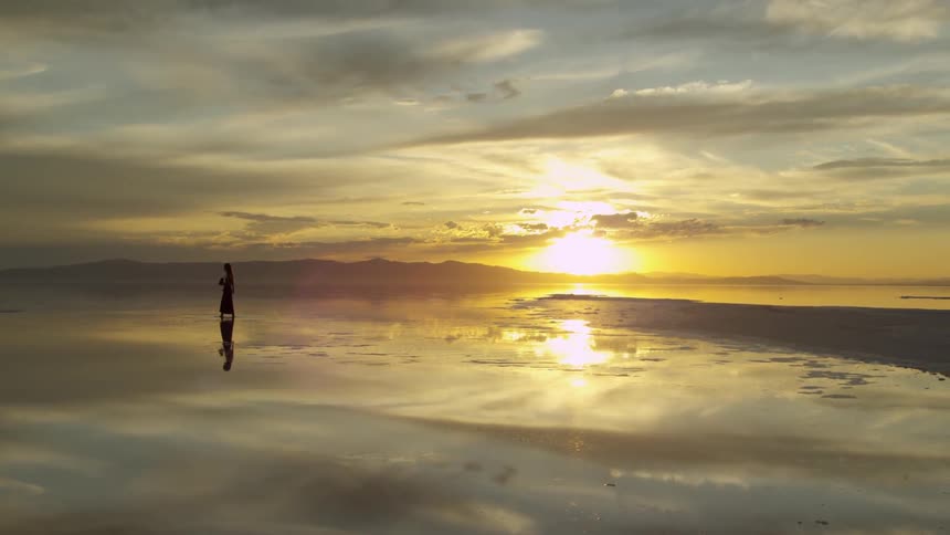 A person is walking along the desert at dawn