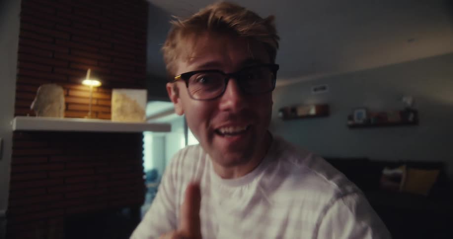 Man talking and waving before showing several pairs of glasses on the table in front of him